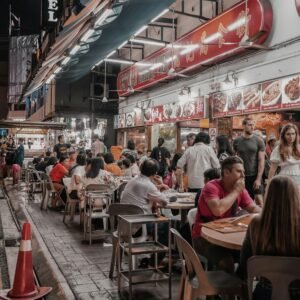 Street food vendor grilling satay skewers while hungry crowds wait at a Kuala Lumpur night market